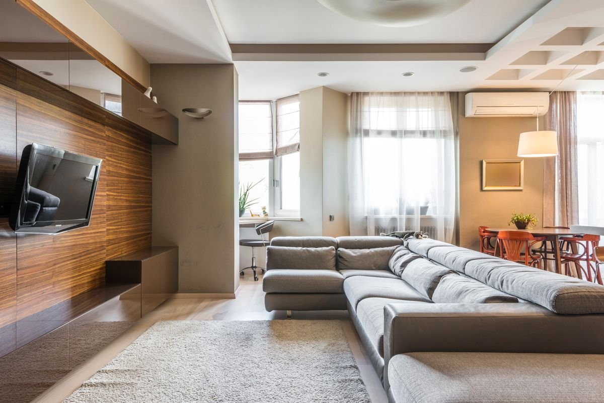 Sala de una vivienda con sofá, iluminación natural y aire acondicionado.